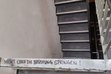 HAU Hebbel am Ufer - Ein Treppengeländer im Backstagebereich, darauf steht in schwarzem Marker "Nicht über die Brüstung springen".